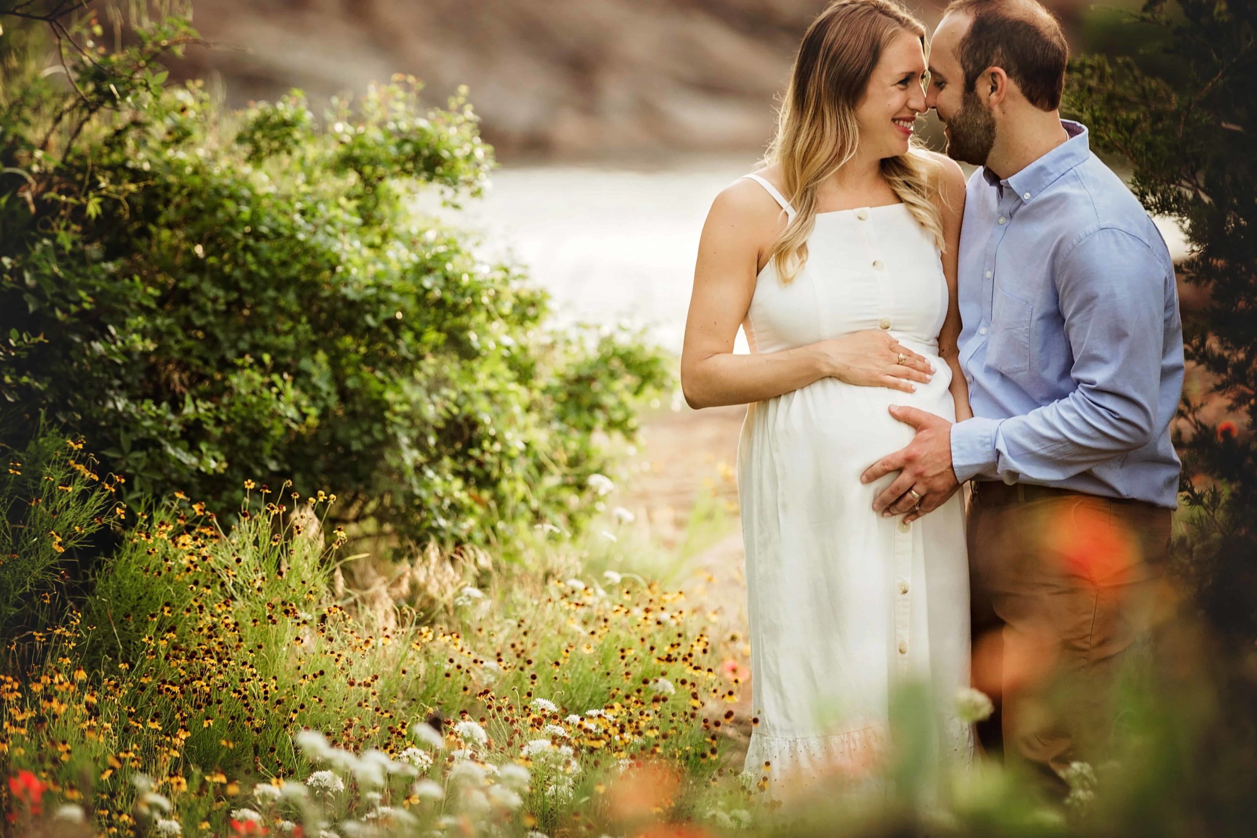 Pregnant Richmond mom and husband embracing with flowers all around them