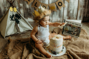 midlothian photographers, baby boy in a crown and about to smash a cake with a wild one first birthday theme