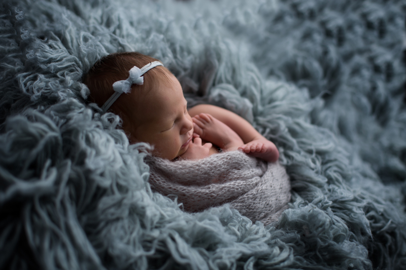 Moseley, Virginia newborn photographer, asleep newborn girl in knit egg wrap pose on blue flokati rug with blue headband