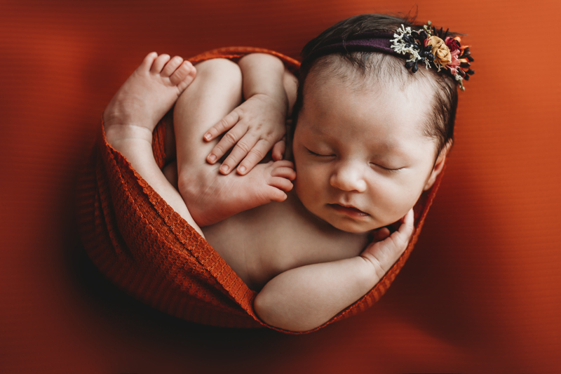 Richmond, Virginia newborn photographers, newborn baby girl wrapped up in a rust colored rap and purple headband