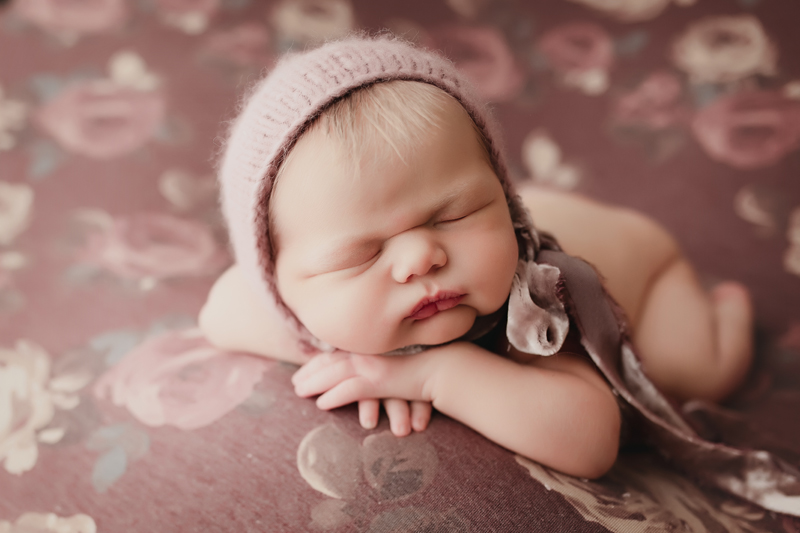 Moseley, virginia newborn photographer, newborn girl with dusty pink knit bonnet asleep on dusty mauve flowery backdrop