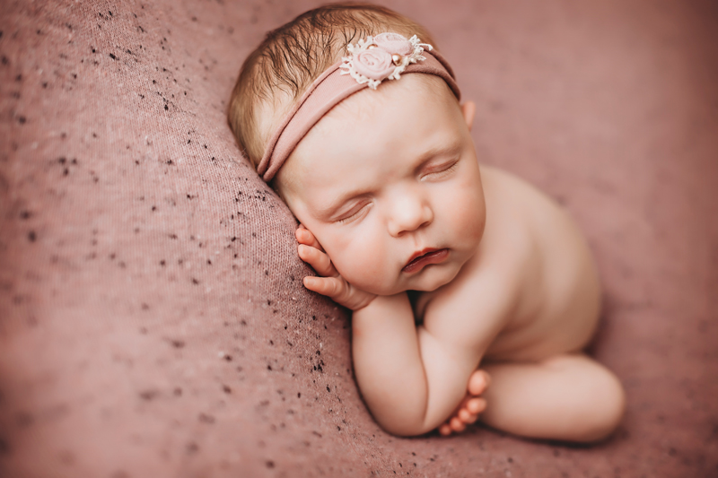 Edmond, Oklahoma newborn photos, newborn baby girl asleep on dusty pink backdrop with pink headband