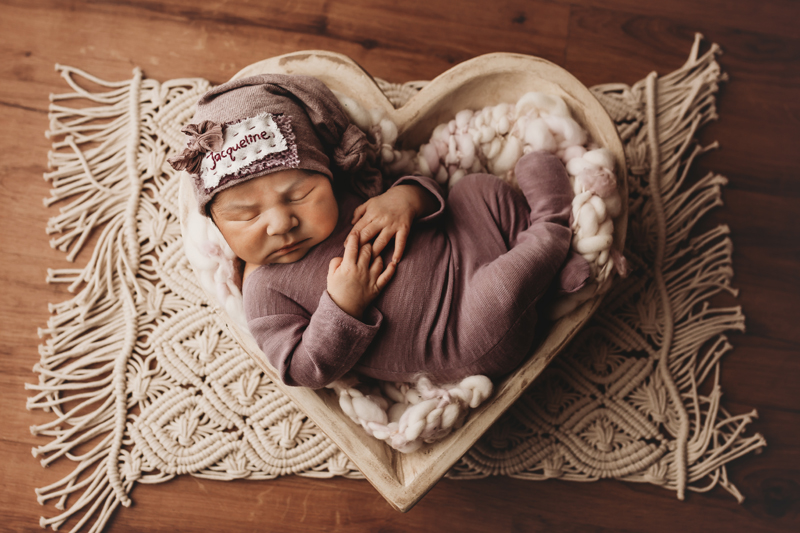 Richmond, Virginia newborn photos, baby girl in purple outfit in white heart bowl asleep on macrame