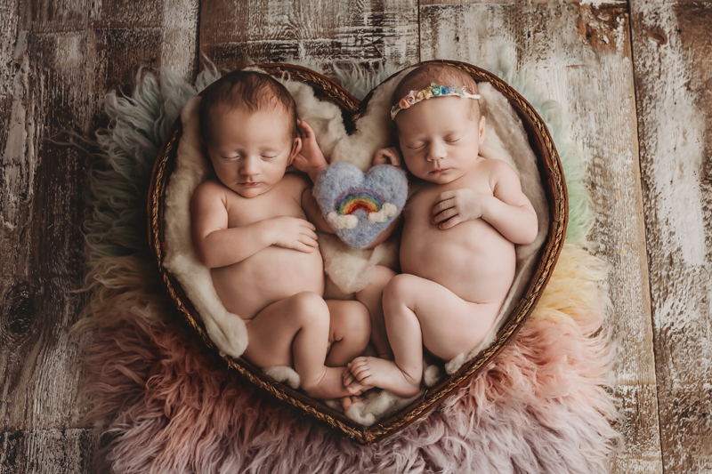 Lawton, Oklahoma newborn photographer, twin newborn babies in a heart wood bowl with a rainbow felt piece in the middle of them