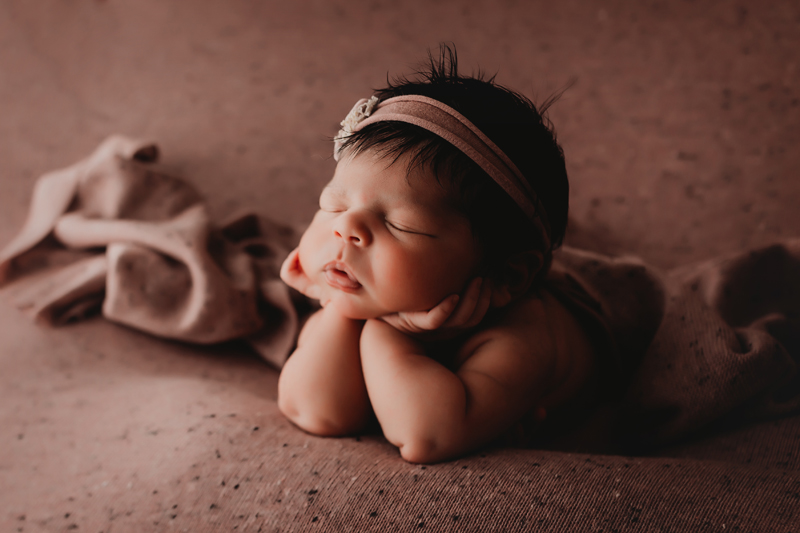 midlothian, virginia newborn photographer, newborn girl on dusty mauve freckled fabric in froggy pose with headband in her hair asleep