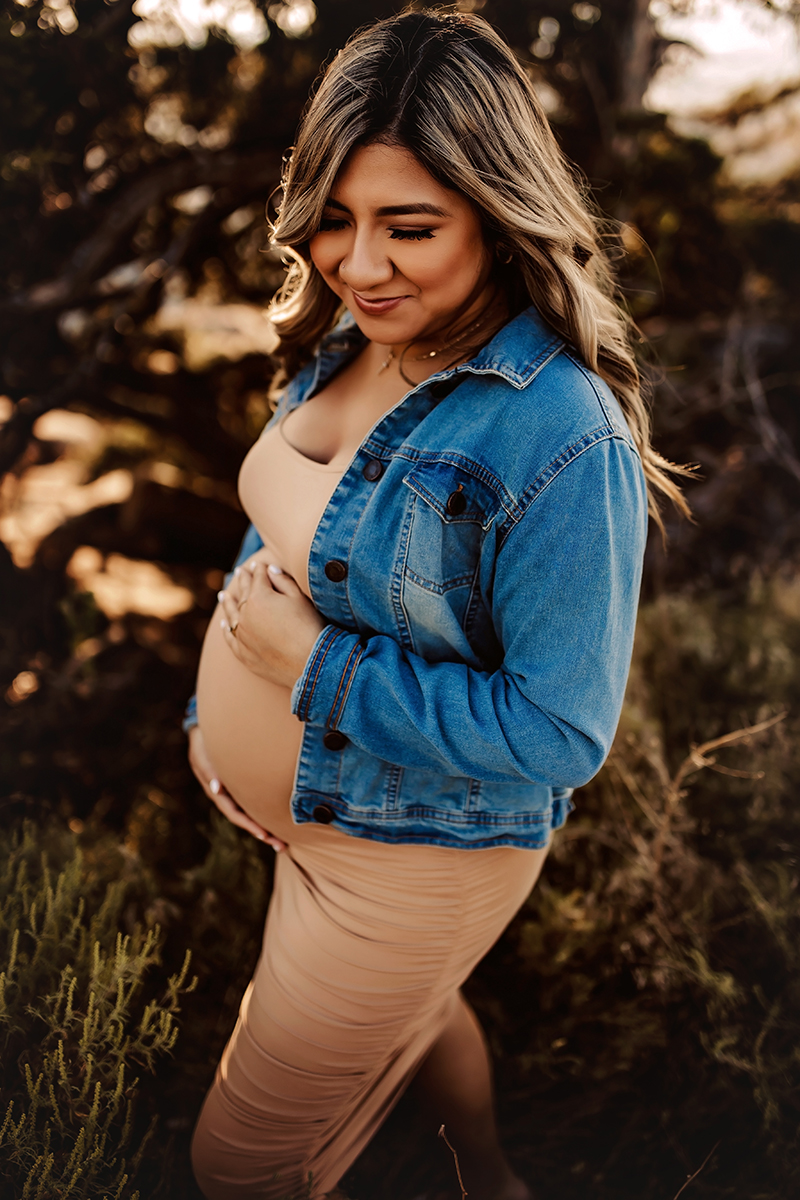 lawton photographer, woman with long hair in tan dress and blue jean jacket holding baby belly