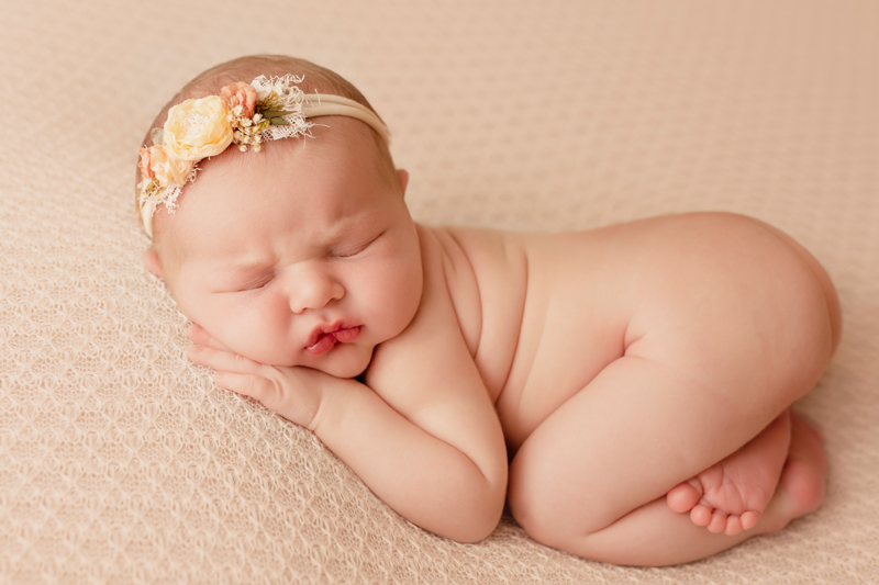 Richmond, Virginia newborn photos, light-skinned newborn baby girl sleeping in bum up pose on ivory background with a flower headband