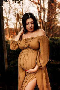 Charlottesville, Virginia maternity photographer, pregnant woman with dark long hair holding her belly in tan boho dress