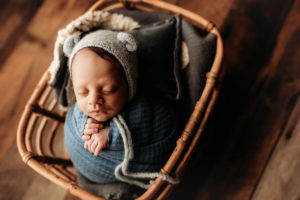 Lawton newborn photographer, baby boy in basket wrapped with knit bear hat,