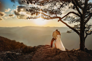 pregnant mama and husband standing together and cradling bump on mountaintop with trees and blue ridge mountains photography behind them, Richmond photographer, rva photographer, midlothian photographer