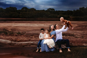 Family sitting on tree branch at the Red River with blue stormy sky in the background of Oklahoma