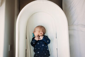 Baby boy in bassinet sucking on pacifier