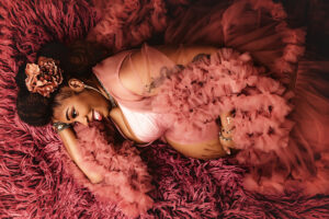 Richmond maternity photographer with black mama lying on her side in tulle pink dress on pink flokati rug