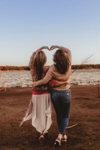 Moseley, Virginia photographer, teenage daughter and mom with arms over head making heart facing water