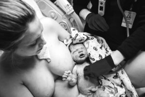 Charlottesville birth photographer, mom holding baby she just birthed while nurse uses stethoscope to listen to her breathing