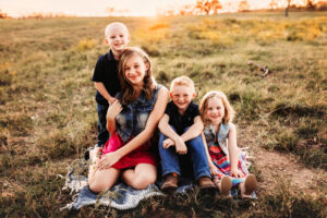 Wichita Falls Texas photographer, four young kids sitting in the grass smiling at the camera