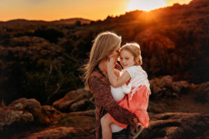 Wichita Falls photographer, lawton photographer, Oklahoma photographer, lawton Oklahoma photographer, north Texas photographer, mom holding young daughter with her hand on her cheek in the sun