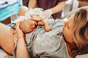 Charlottesville Virginia birth photographer, mom in hospital gown holding the baby she just birthed